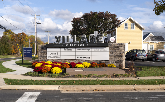 Outdoor signage with shrubs in front at Village at Newtown in Newtown, Pennsylvania