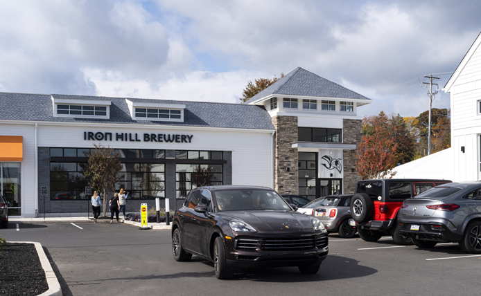 Black car driving in front of Iron Hill Brewery at Village at Newtown shopping center