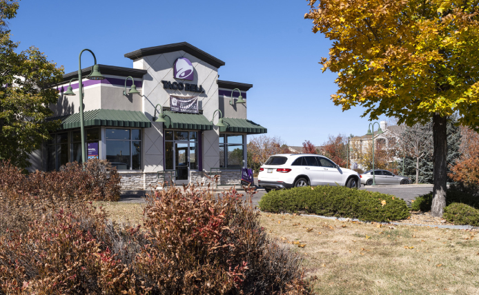 White Car, bushes and trees in front of Taco Bell.