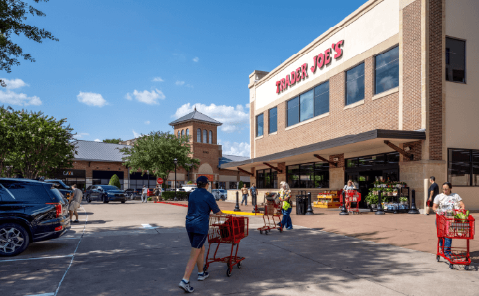 Shoppers with carts approach Trader Joe's through the parking lot.