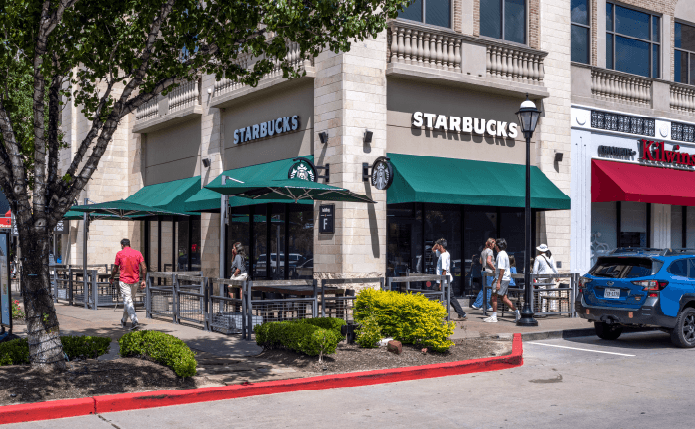 Starbucks with patrons by right window and outdoor seating on the left.