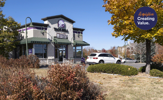 Taco Bell with bushes and trees surrounding drive thru.