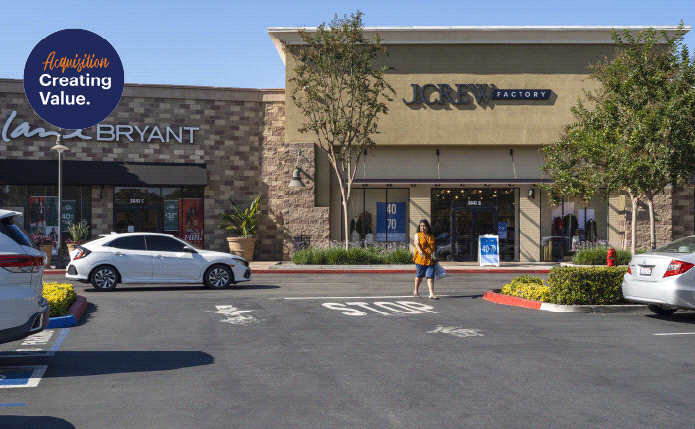 White car approaches JCrew Factory with a tree on the right.