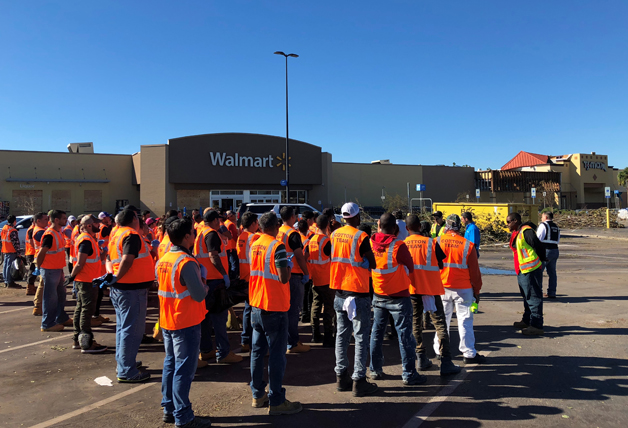 Group of volunteers listening to director, all wearing safety vests