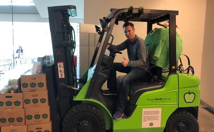 person at Houston Food Bank sitting in a forklift carrying boxes