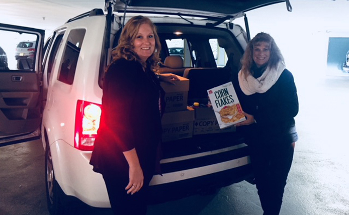 Brixmor volunteers standing next to trunk of SUV with donations