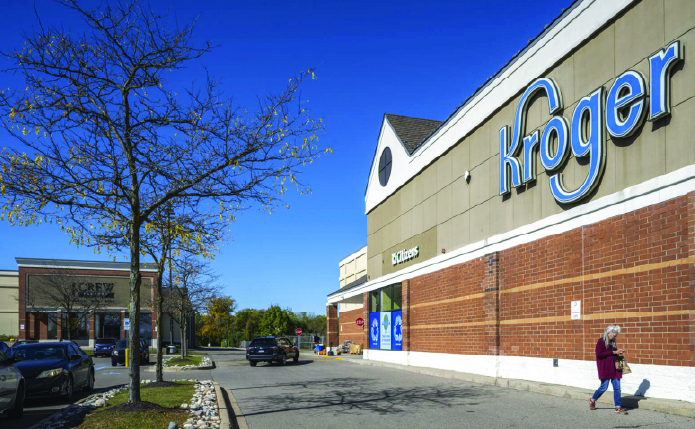 Woman passing under Kroger sign on access road.