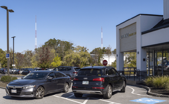 Car parked in front of Life Alive Cafe with trees in background.