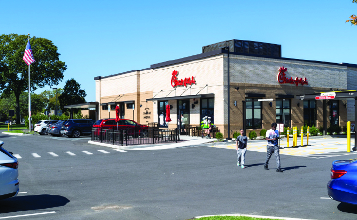 Two people leave Chic Fil A into crosswalk.