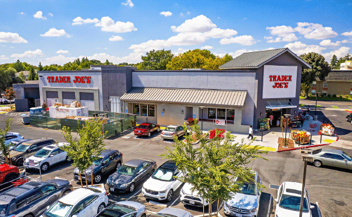 Parking lot and trees surround aerial view of Trader Joe's.