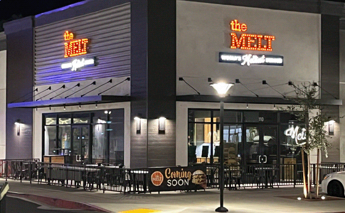 The Melt with outdoor seating in front at night.