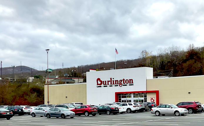 Burlington storefront on cloudy day with trees and cars around store.