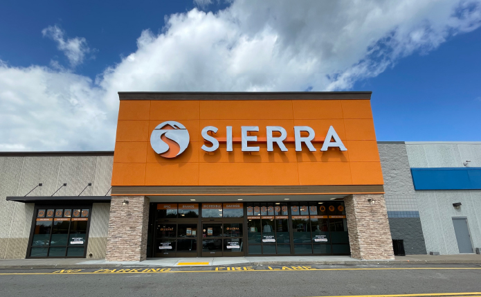 Bright orange façade at Sierra storefront with blue cloudy sky above.