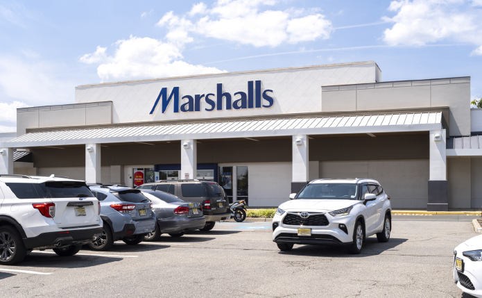 Marshalls parking lot with white car passing in lot.