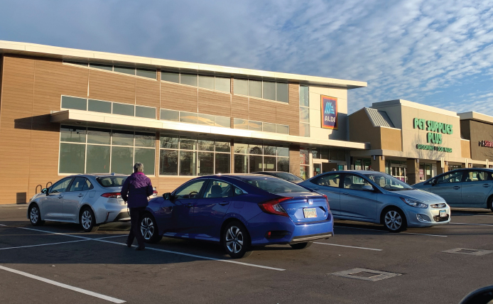 Person walking between parked cars at Aldi and Pet Supplies Plus at Roseville Center