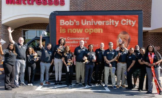 Group of employees at storefront of opening of Bob's Discount Furniture.