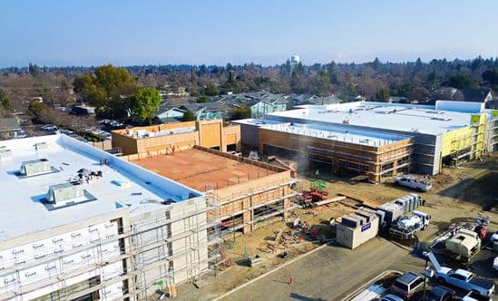 Aerial view of The Davis Collection redevelopment with buildings under construction, scaffolding, and active job site equipment.
