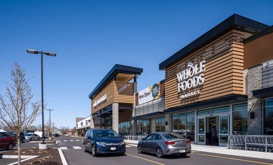 Two cars passing in the drive lane on front of Whole Foods Market at Barn Plaza shopping center