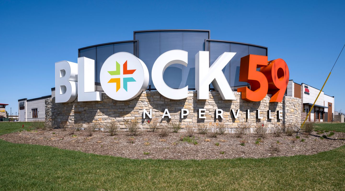 Block 59 monument signage in Naperville, IL marking the completed redevelopment featuring new retail, dining destinations, modern architecture, and enhanced site identity.