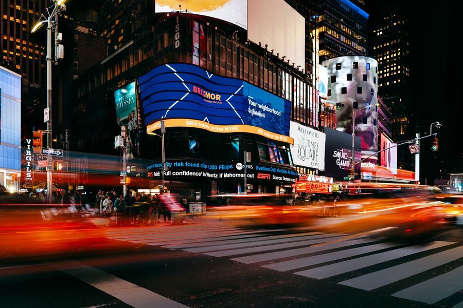 Brixmor featured on a NYSE digital billboard in Times Square in New York City at night with blurred car traffic in front