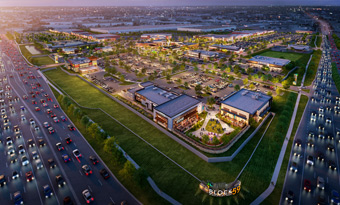 Aerial twilight rendering of Block 59 in Naperville, IL, showcasing the full mixed‑use development with multiple restaurant and retail buildings, illuminated pedestrian areas, landscaped open spaces, extensive parking fields, and adjacent highway traffic flowing along the site’s frontage.