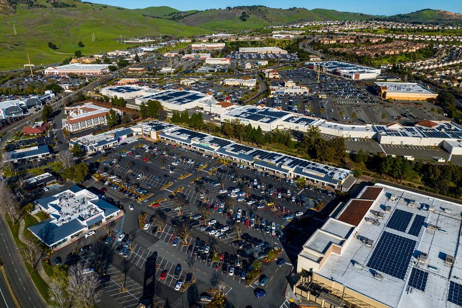 Aerial view of two open air shopping centers with solar panels on the rooftops