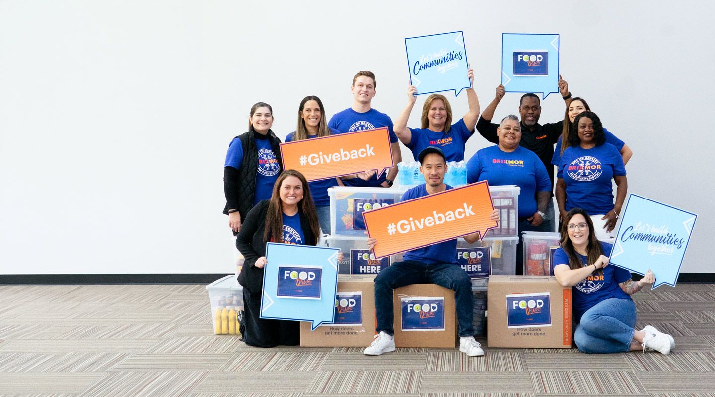 Group of employees sitting on boxes with give back signs