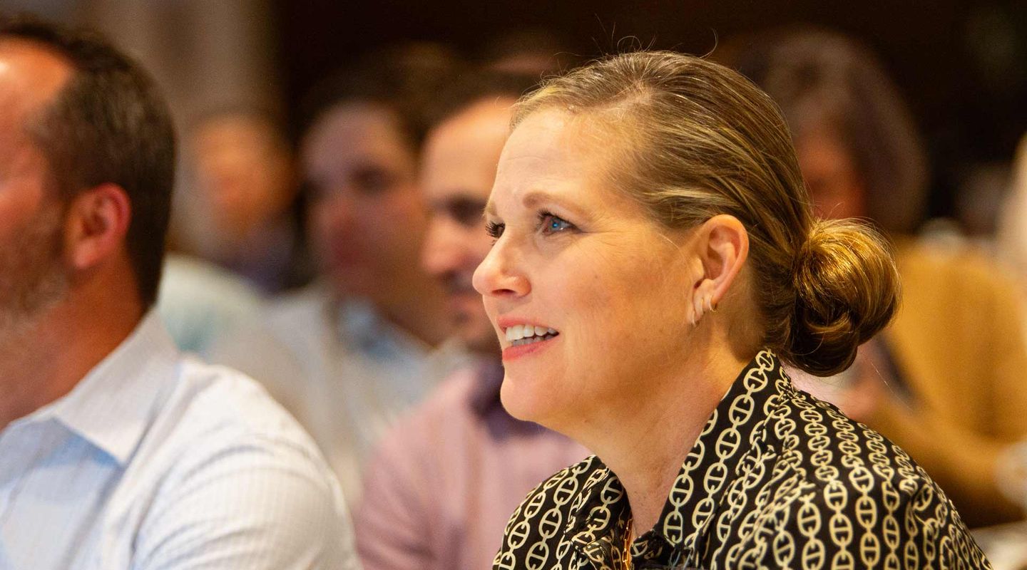 A woman seated in a crowd watching a speaker who is offscreen