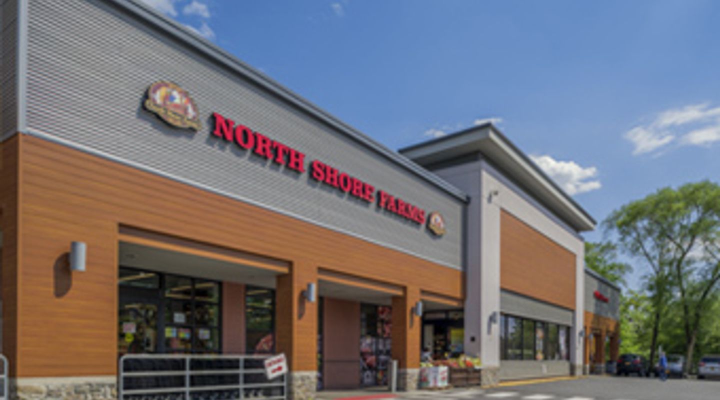 North Shore Farms at Mamaroneck Centre in Mamaroneck, NY, featuring contemporary exterior design with horizontal metal cladding, wood‑accent panels, stone base detailing, and landscaped walkways leading to the grocery entrance.