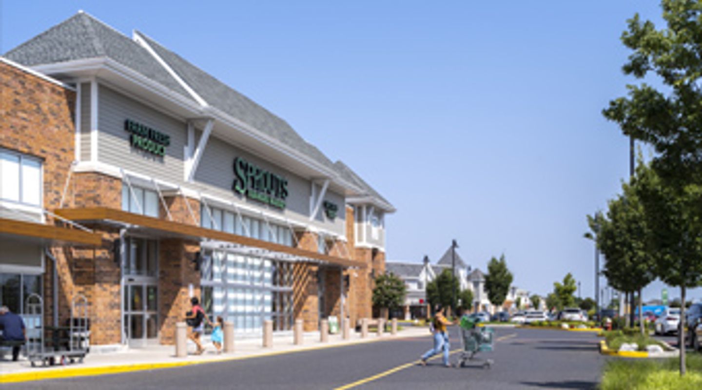 Sprouts Farmers Market at Marlton Crossing in Marlton, NJ, featuring a contemporary grocery façade with brick and white siding accents, green signage, large storefront windows, and active shopper traffic in the parking area.