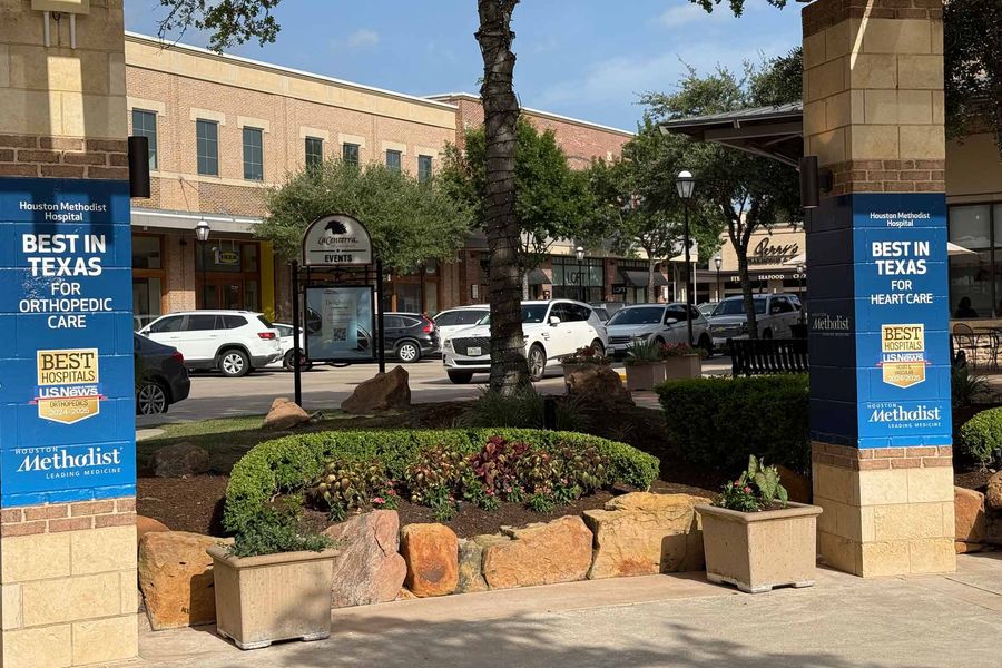 Exterior view of courtyard with Hospital banners on columns at LaCenterra at Cinco Ranch in Houston TX