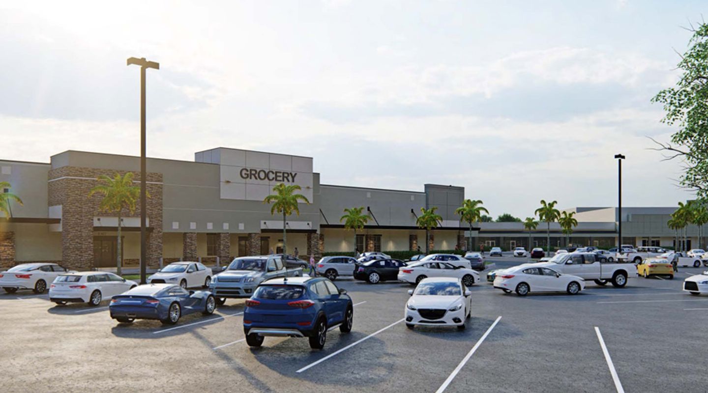 Updated grocery‑anchored retail building at Sunrise Town Center in Sunrise, FL, shown with stone accent columns, wide sidewalks, palm‑lined frontage, and customer vehicles filling the surrounding parking area.