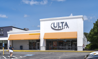 Ulta Beauty at Watertower Plaza in Leominster, MA, featuring a bright white façade with orange awnings, large storefront windows, accessible parking spaces, and a paved drive aisle under a sunny blue sky.