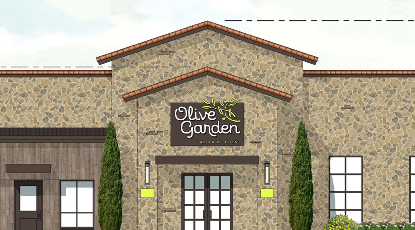 Architectural rendering of an Olive Garden restaurant at Wynnewood Village in Dallas, TX, featuring a stone façade with Mediterranean‑inspired detailing, clay tile roof accents, tall evergreen landscaping, and a prominent branded entryway.